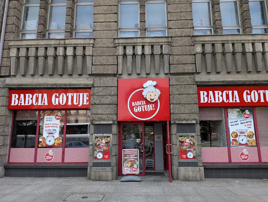 Czerwony szyld BABCIA GOTUJE nad witrynami